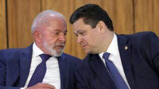 A imagem é um close-up que captura o presidente Luiz Inácio Lula da Silva e o senador Davi Alcolumbre em uma conversa íntima e concentrada, lado a lado.