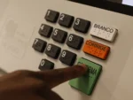 urna eletrônica de votação com foco nos botões em especial um dedo indicador apertando o botão verde