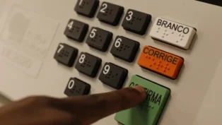 urna eletrônica de votação com foco nos botões em especial um dedo indicador apertando o botão verde