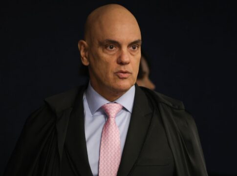 A imagem é um plano médio que foca no ministro do Supremo Tribunal Federal (STF), Alexandre de Moraes, em um ambiente interno e formal.