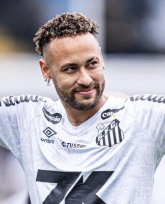 A imagem é um plano médio do jogador de futebol Neymar Jr., vestindo a camisa do Santos Futebol Clube, em um momento de interação com o público ou torcida.