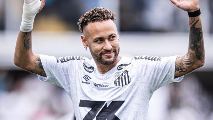 A imagem é um plano médio do jogador de futebol Neymar Jr., vestindo a camisa do Santos Futebol Clube, em um momento de interação com o público ou torcida.