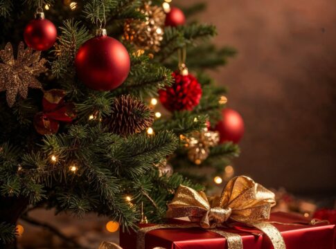 Na foto há uma árvore de natal decorada e do lado há presentes em embrulho vermelho.