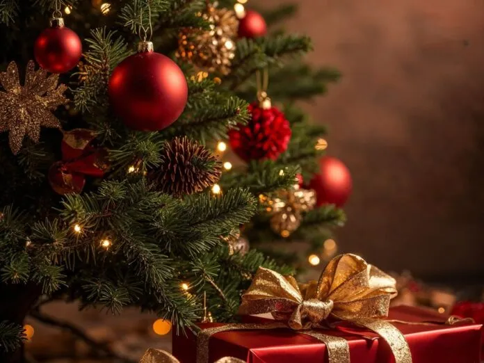 Na foto há uma árvore de natal decorada e do lado há presentes em embrulho vermelho.