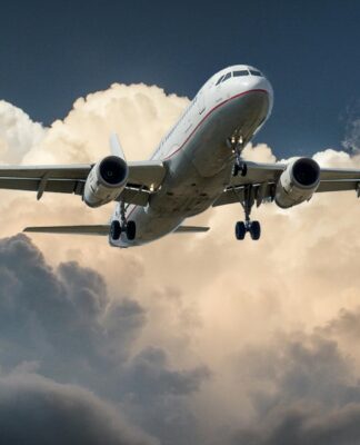 avião branco no céu com nuvens brancas ao fundo e céu azul