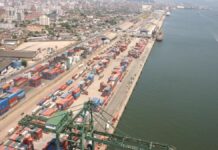 Esta é uma vista aérea ampla que captura uma seção do Porto de Santos no Brasil, destacando a intensa atividade de movimentação de contêineres e a proximidade com a área urbana da cidade.