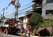 Funcionários da Enel consertam poste de luz