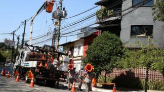 Funcionários da Enel consertam poste de luz