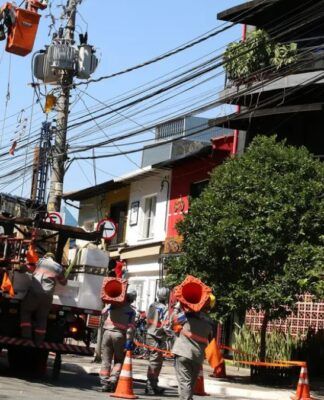 Funcionários da Enel consertam poste de luz