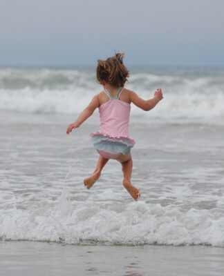Criança pulando onda no mar