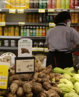 Uma trabalhadora aparece, de costas, trabalhando em um supermercado