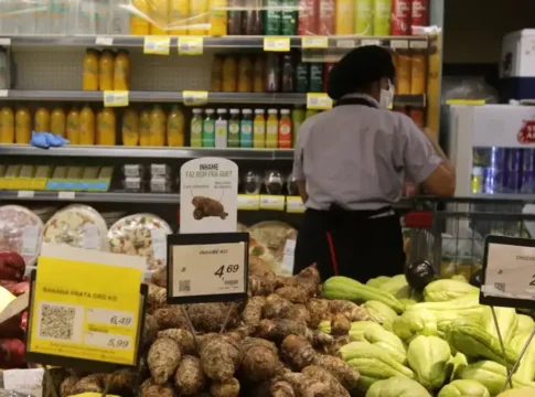 Uma trabalhadora aparece, de costas, trabalhando em um supermercado