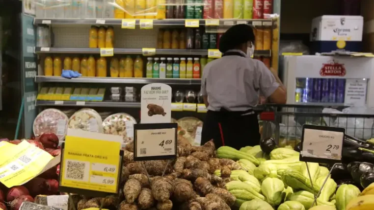 Uma trabalhadora aparece, de costas, trabalhando em um supermercado
