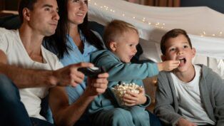 Em imagem ilustrativas família está pronta para assistir um filme em casa