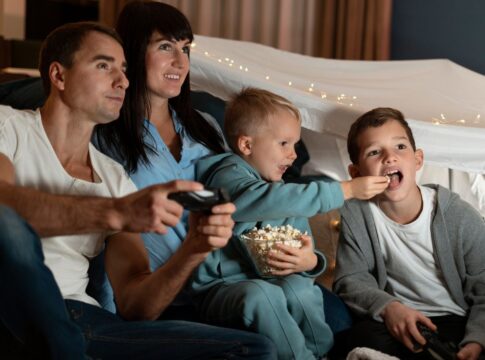 Em imagem ilustrativas família está pronta para assistir um filme em casa