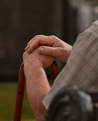 Imagem ilustrativa mostra idoso, sentado em cadeira e usando bengala