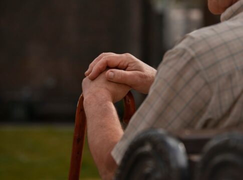 Imagem ilustrativa mostra idoso, sentado em cadeira e usando bengala