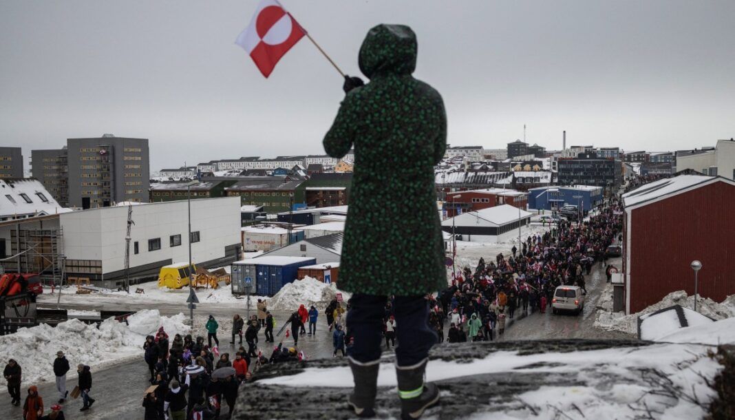 Mulher acena com uma bandeira da Groenlândia durante um protesto contra a exigência do presidente dos Estados Unidos, Donald Trump, de que a ilha no Ártico seja cedida aos EUA