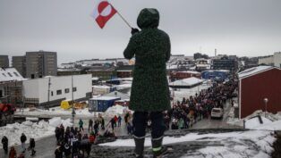Mulher acena com uma bandeira da Groenlândia durante um protesto contra a exigência do presidente dos Estados Unidos, Donald Trump, de que a ilha no Ártico seja cedida aos EUA