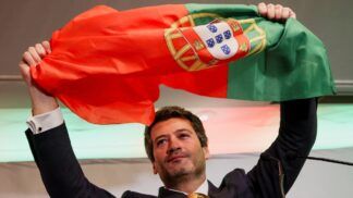O candidato à Presidência de Portugal e líder do partido Chega, André Ventura, segura uma bandeira portuguesa enquanto discursa