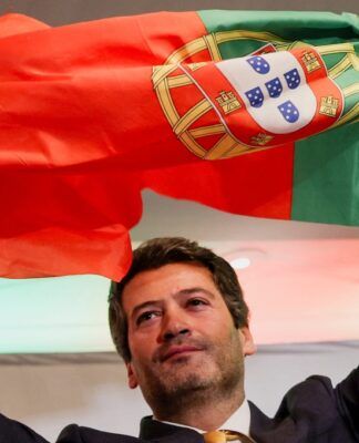 O candidato à Presidência de Portugal e líder do partido Chega, André Ventura, segura uma bandeira portuguesa enquanto discursa