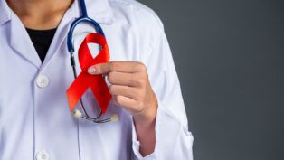 O médico segura um laço vermelho, símbolo da conscientização sobre o HIV, do Dia Mundial de Luta contra a Aids e do Dia Mundial da Saúde Sexual