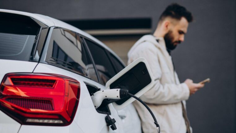 Homem carregando carro elétrico perto da casa