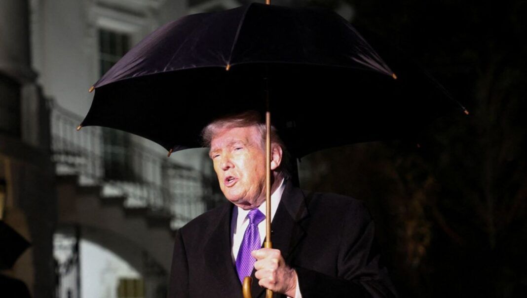 O presidente dos Estados Unidos, Donald Trump, segura um guarda-chuva enquanto fala com jornalistas ao deixar a Casa Branca com destino à Flórida