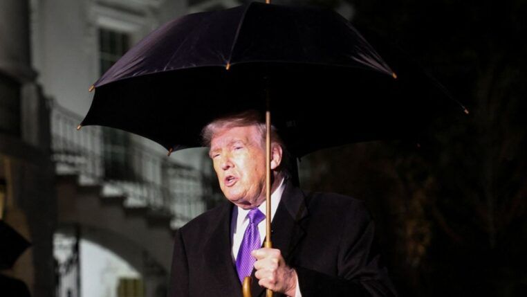 O presidente dos Estados Unidos, Donald Trump, segura um guarda-chuva enquanto fala com jornalistas ao deixar a Casa Branca com destino à Flórida