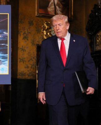 O presidente dos Estados Unidos, Donald Trump, passa por uma imagem de projeção do navio da “Classe Trump”, o USS Deifant, em Mar-a-Lago, em Palm Beach, na Flórida