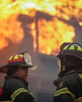 Bombeiros diante de uma casa pegando fogo no Chile