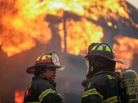 Bombeiros diante de uma casa pegando fogo no Chile