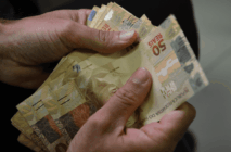 Duas mãos contam notas de 50 reais