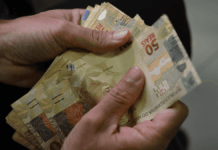 Duas mãos contam notas de 50 reais