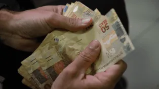 Duas mãos contam notas de 50 reais