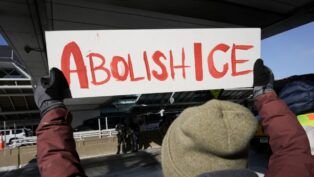 Pessoa segura um cartaz escrito: "Abolish ICE"
