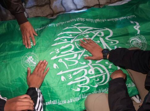 Homens com as mãos sobre uma bandeira do Hamas