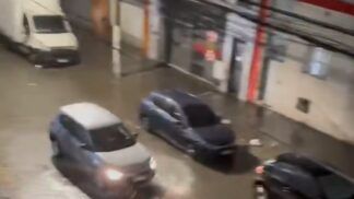 Carros passam por rua alagada em São Paulo