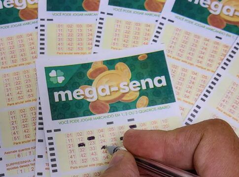 Uma mão assinala números na cartela da Mega-Sena