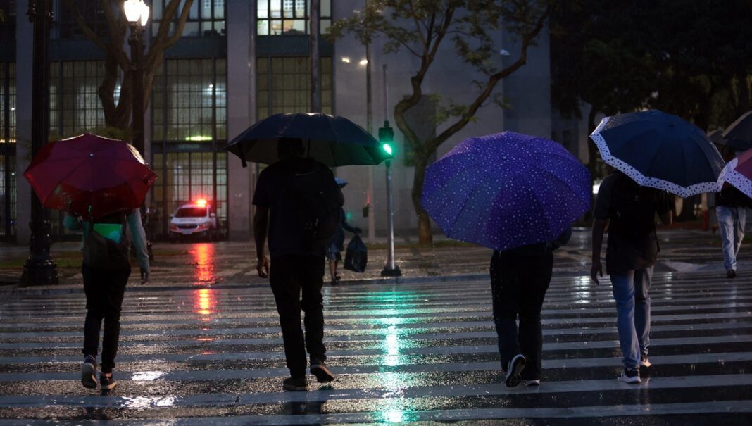Pessoas usam guarda-chuva durante chuva no centro da cidade