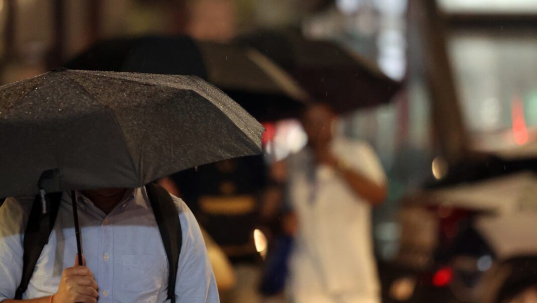 Pessoas durante chuva na Avenida Paulista.