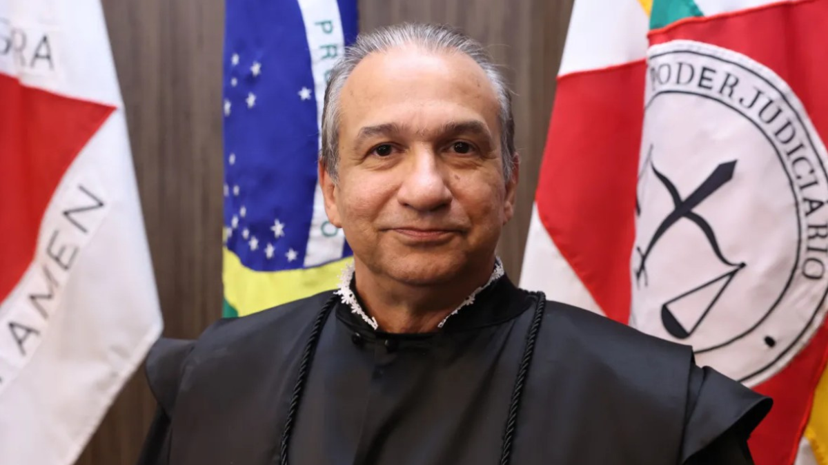 Desembargador Magid Láuar de toga em frente a várias bandeiras