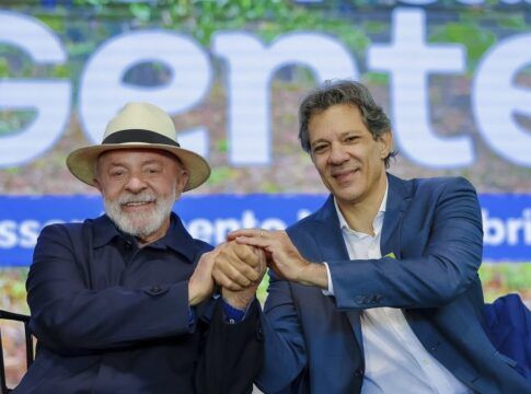Lula e Haddad apertam as mãos durante cerimônia de entregas do Programa Terra da Gente no estado do Paraná