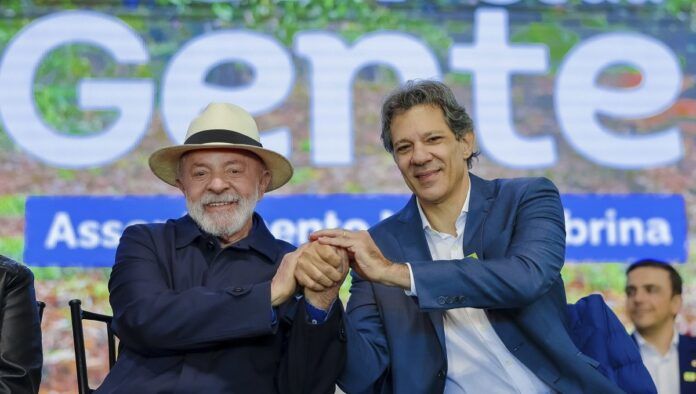 Lula e Haddad apertam as mãos durante cerimônia de entregas do Programa Terra da Gente no estado do Paraná