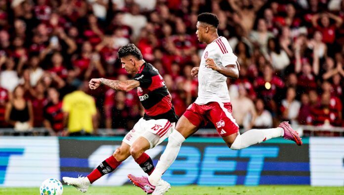 Jogador do Flamengo em disputa de bola com atleta do Inter