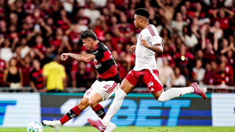 Jogador do Flamengo em disputa de bola com atleta do Inter