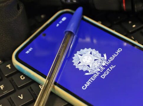 Imagem da carteira de trabalho virtual, na tela de um celular, e uma caneta