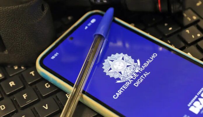 Imagem da carteira de trabalho virtual, na tela de um celular, e uma caneta