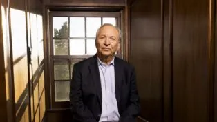 Larry Summers posa para foto sentado à frente de uma janela