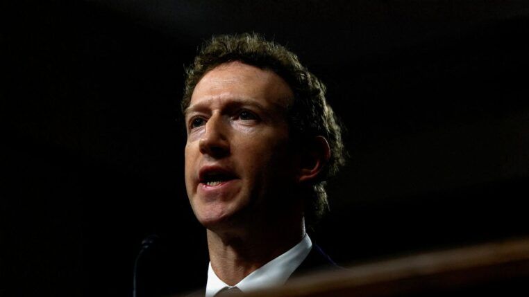 Mark Zuckerberg aparece de terno e gravata diante de um fundo escuro